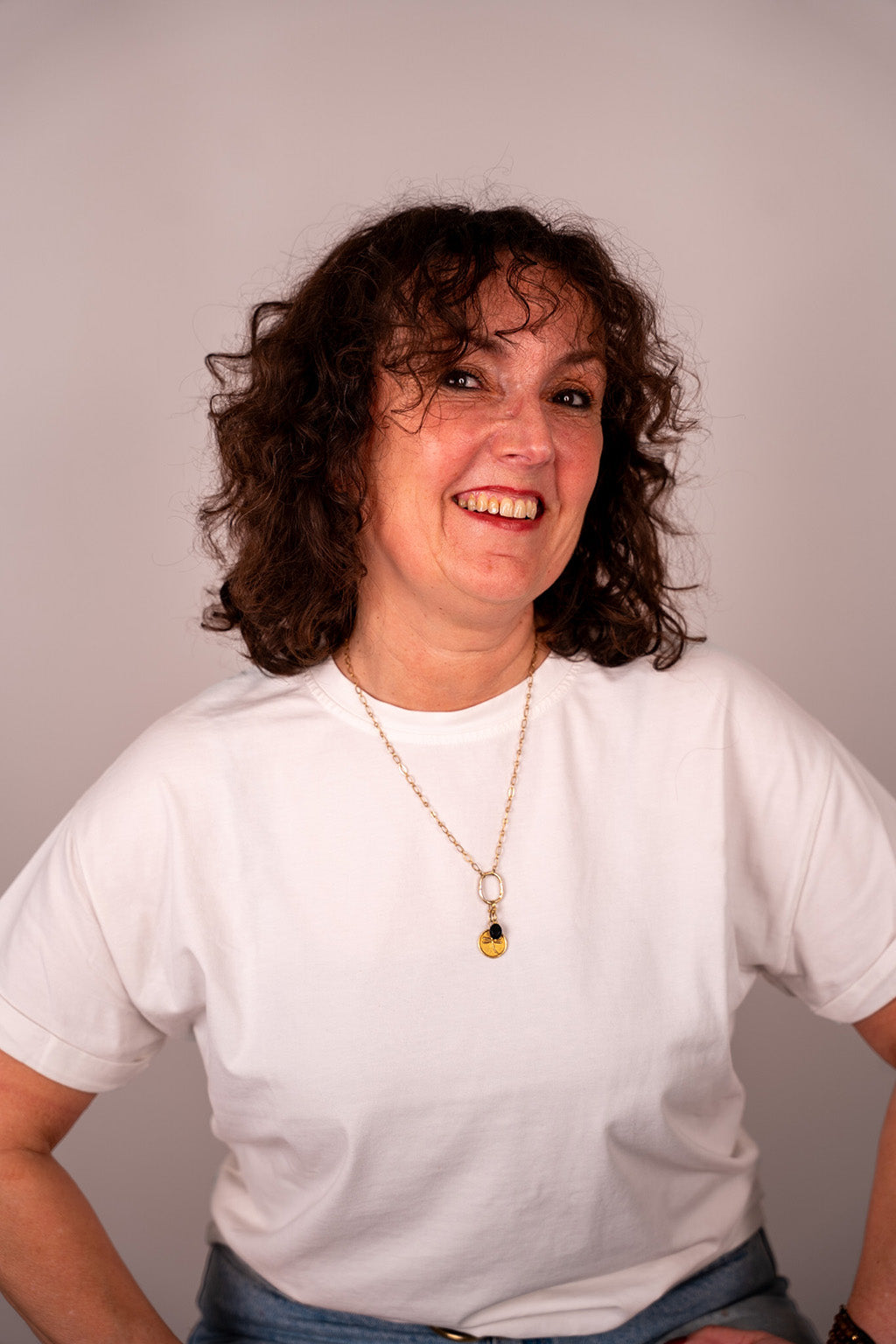 Person wearing a white t-shirt and blue jeans with a plain background