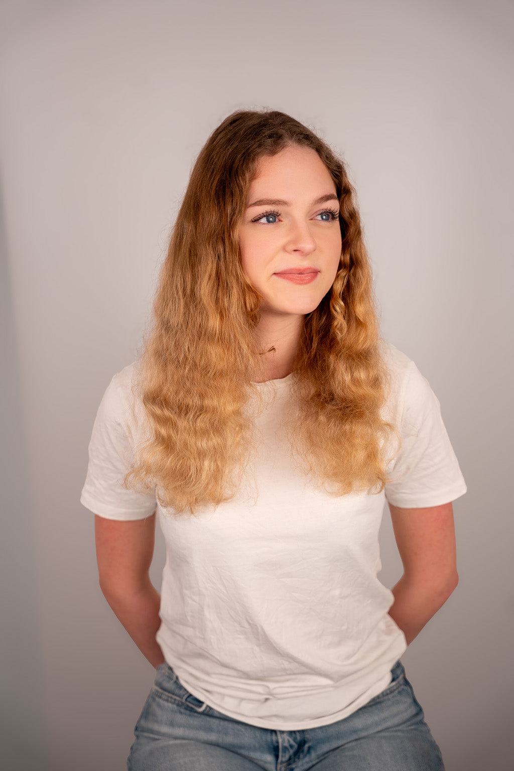 Person wearing a white t-shirt and blue jeans against a plain background