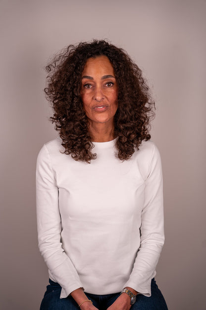 Woman wearing a white sweater against a plain background