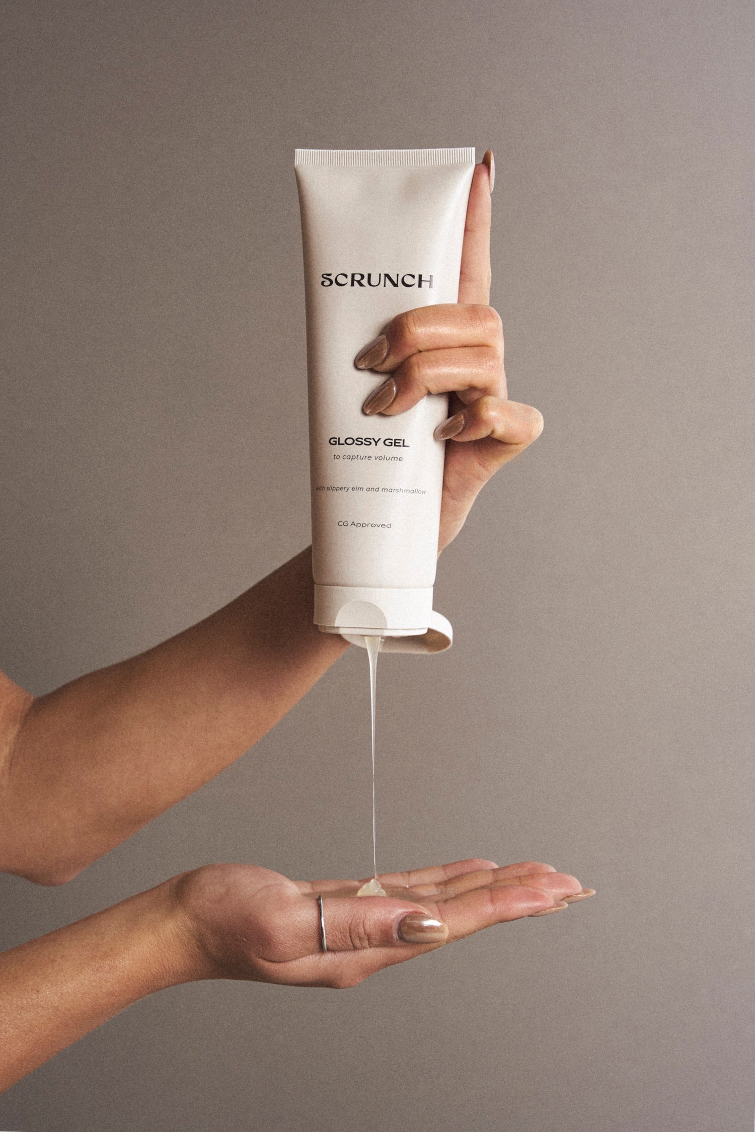 Hand holding a tube of Sorinch Glossy Gel with a gray background