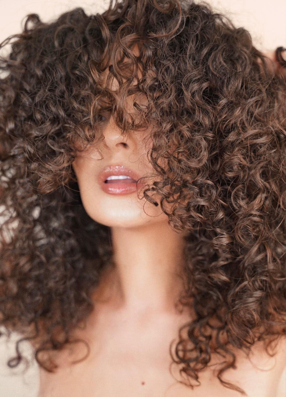 Woman with voluminous curly hair covering her face