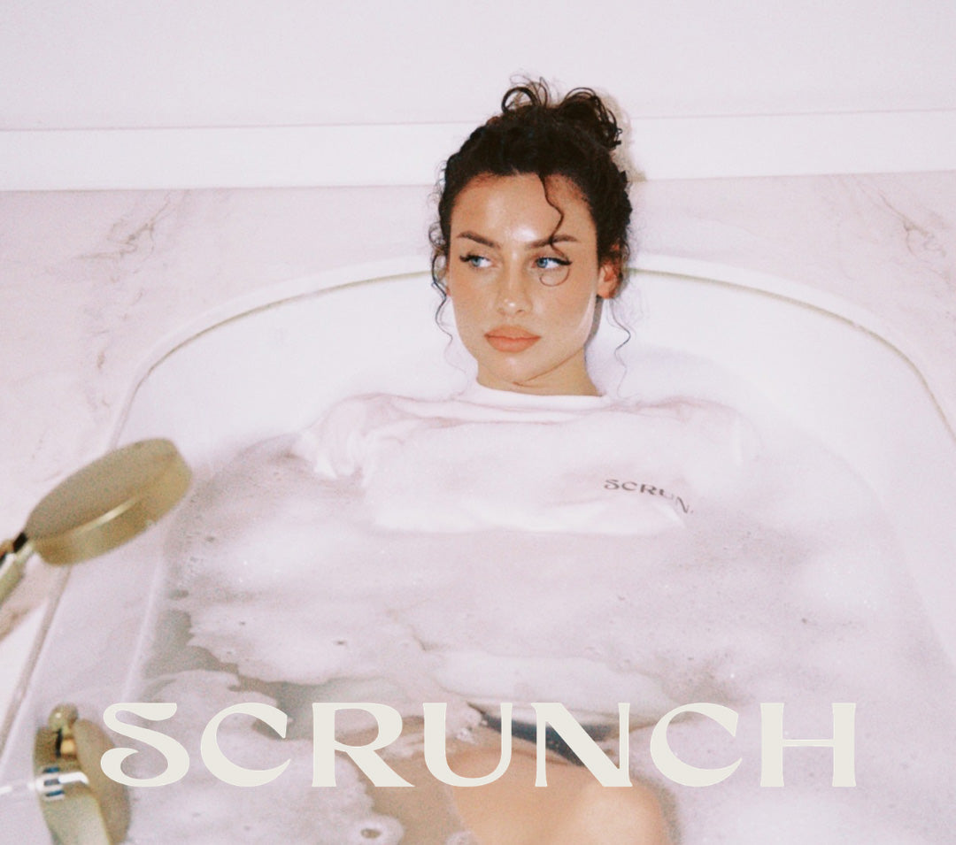 Person lying in a bubble bath with 'SCRUNCH' branding.